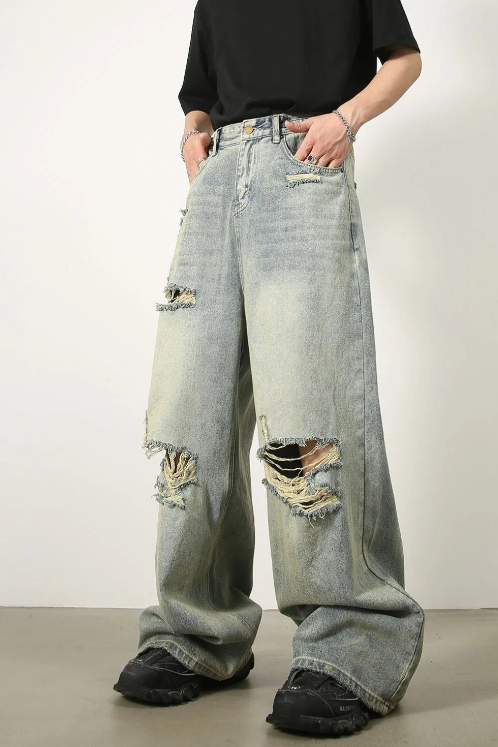 Light wash distressed denim palazzo trousers with a wide leg and ripped details.