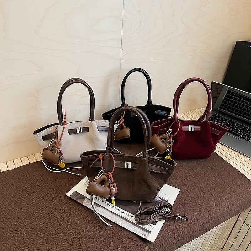 Elegant suede and leather mini tote bags in dark gray, coffee brown, burgundy, and black with charm details.