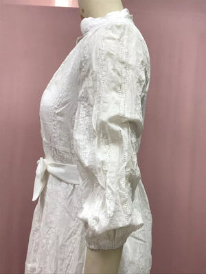 White eyelet dress with puff sleeves, high neck, and sash belt.