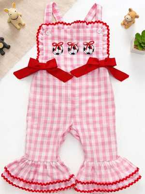 Gingham soccer ball embroidered jumpsuit in blush pink cotton with red bows and ruffled bell bottoms.