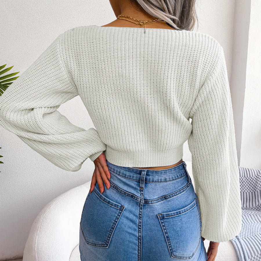 White ribbed knit crop top with balloon sleeves and a V-neckline, styled with jeans.