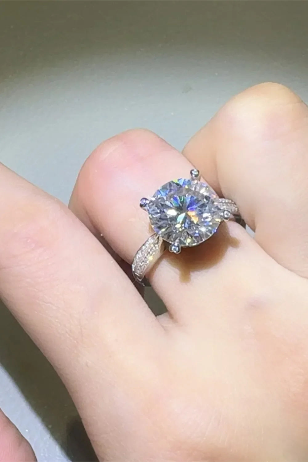 Silver pavé band round moissanite engagement ring with a large center stone.