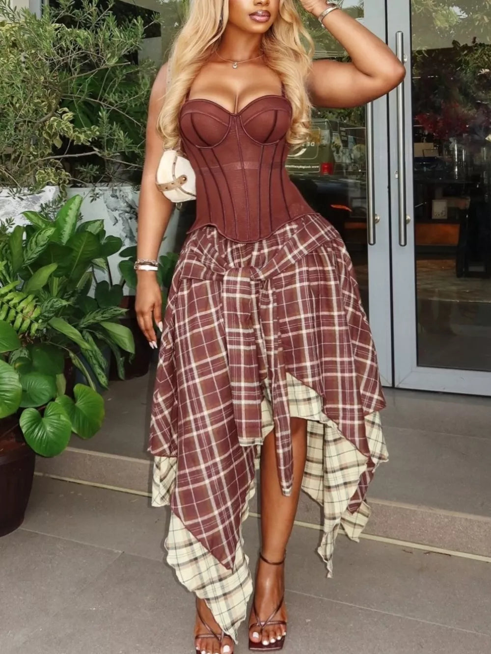 Brown corset cami with layered plaid asymmetrical skirt ensemble.