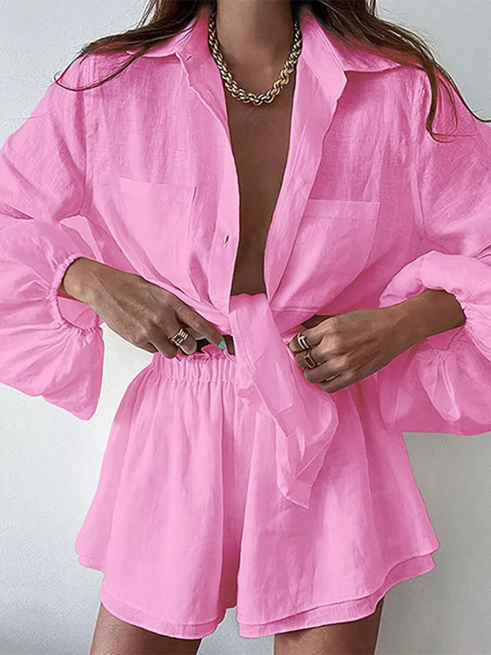 Pink two-piece shirt and shorts set with tie front, button-up shirt, and ruffled sleeves.