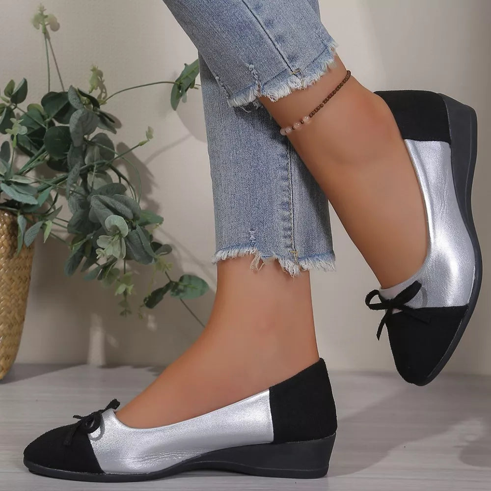 Black and silver slip-on flats with bow detail.
