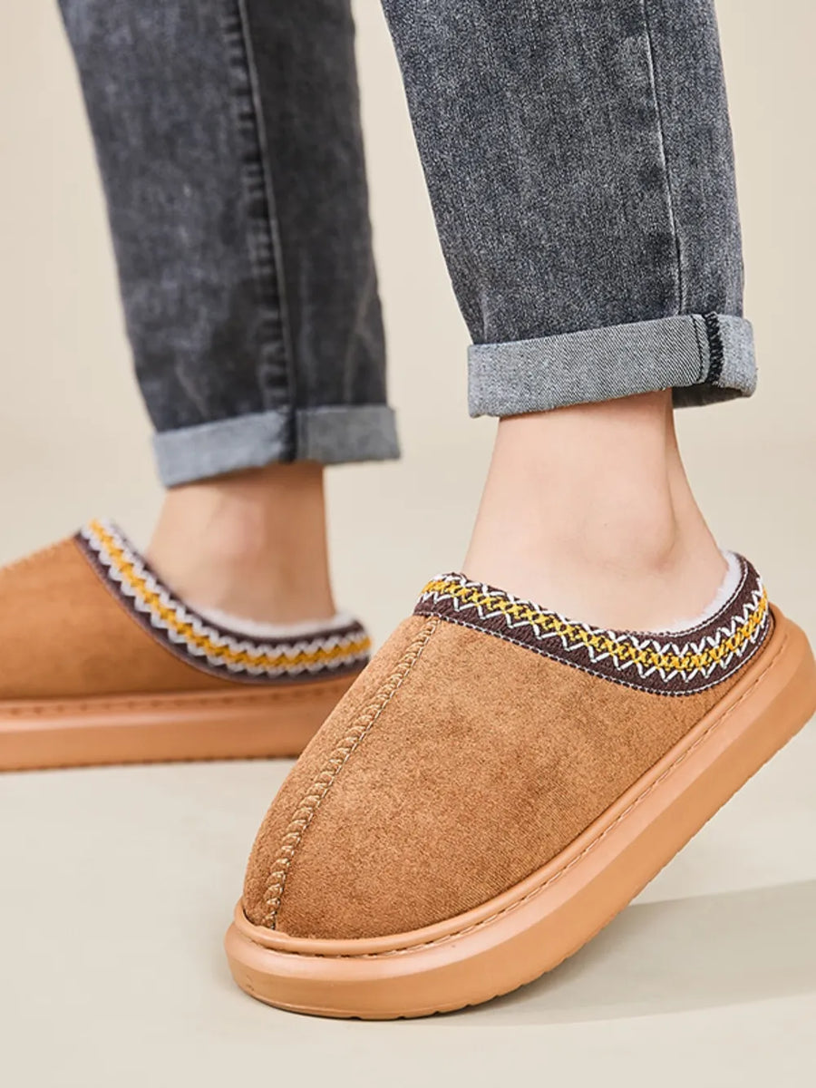 Caramel shearling house slippers with embroidered trim and faux fur lining.