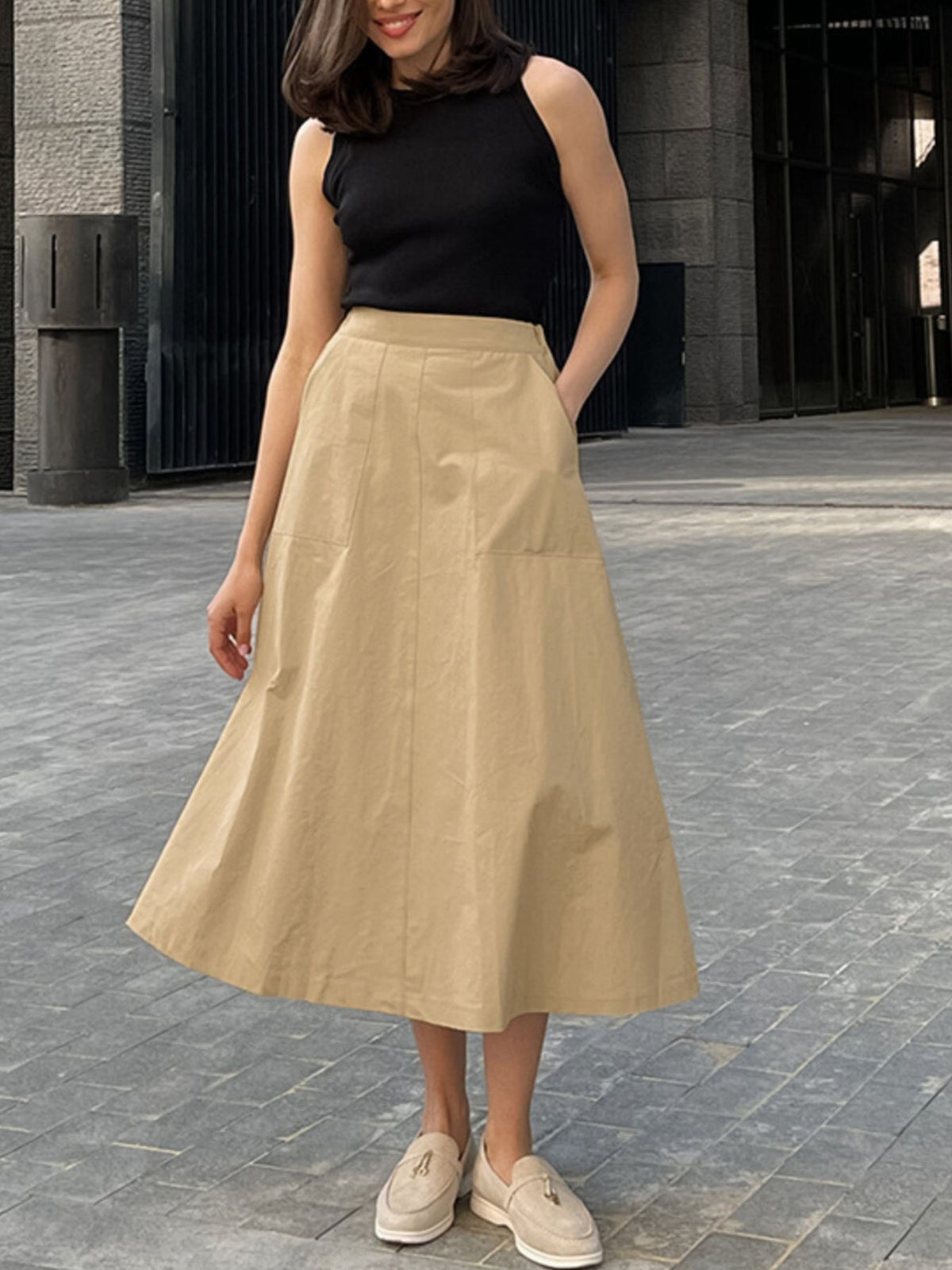 High-waisted A-line skirt in tan cotton with patch pockets and a midi length.
