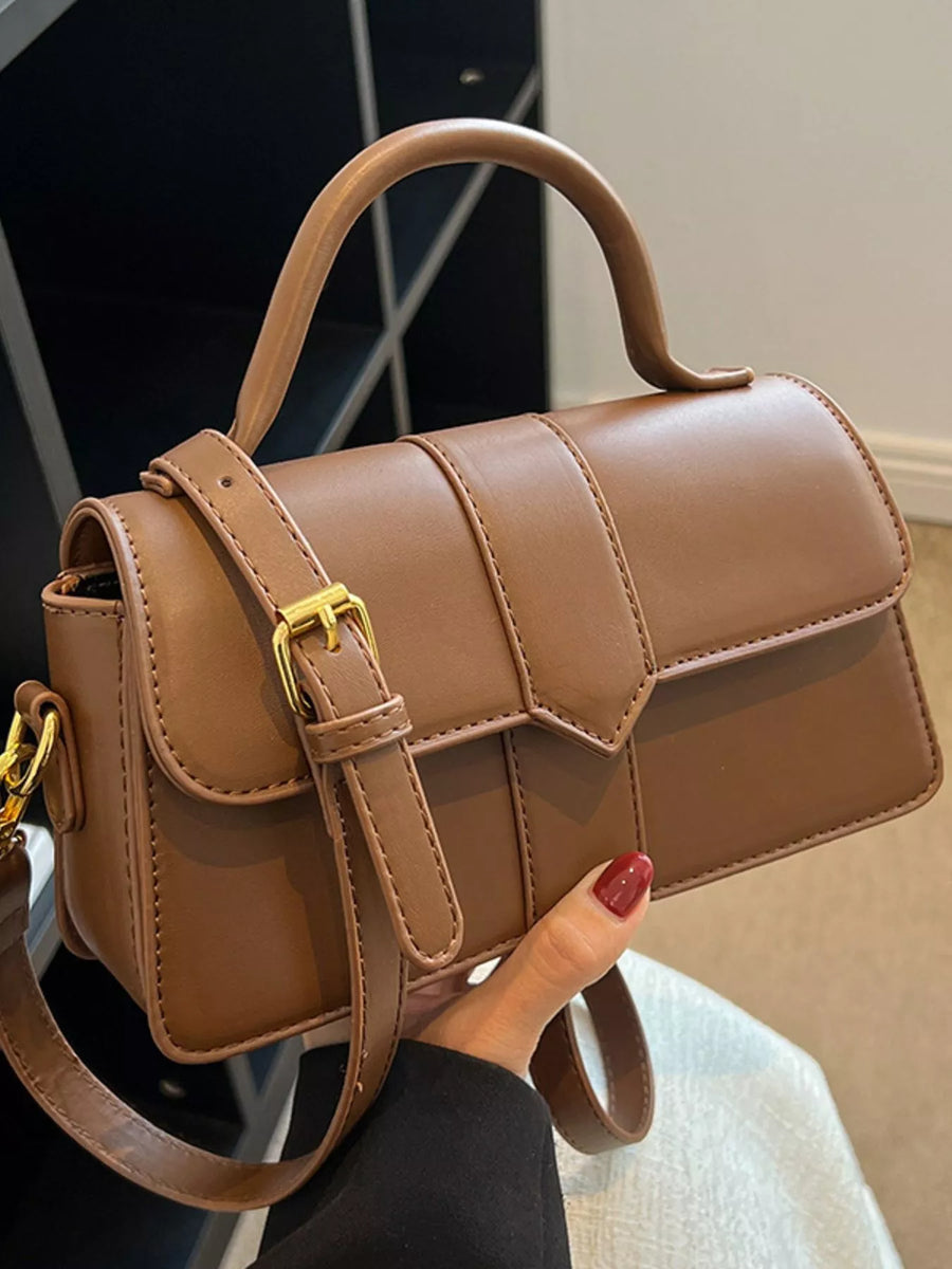 Chic small top handle bag in brown with gold buckle detail and adjustable strap.
