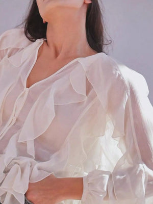White sheer long-sleeve blouse with ruffled neckline and cuffs