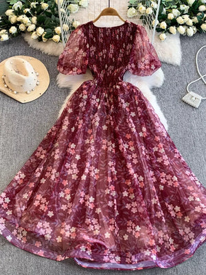 Crimson floral maxi dress with smocked bodice and sheer puff sleeves.