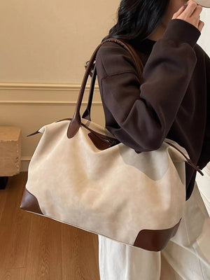 Chic slouchy travel bag in beige suede with brown leather accents and handles.
