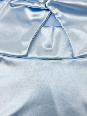 Light blue satin top with twisted neckline detail and visible stitching.