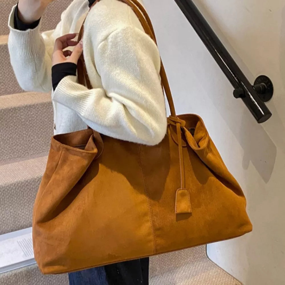 Ochre suede slouchy shoulder bag with drawstring and top handle.