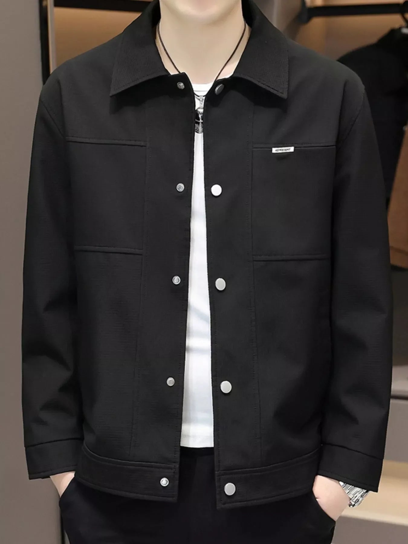 Men's black snap down jacket with collar and chest pockets.