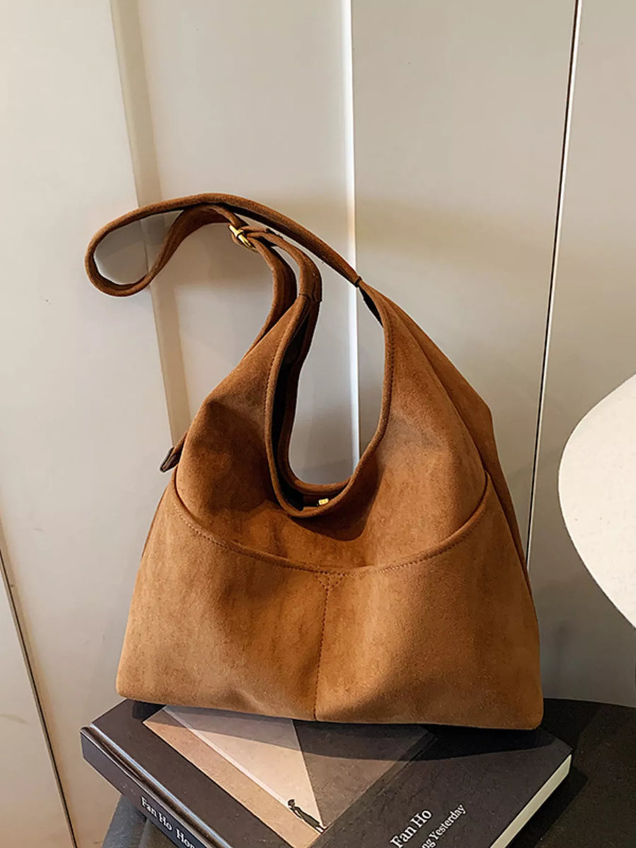 Large brown suede shoulder bag with a slouchy silhouette and front pocket detail.