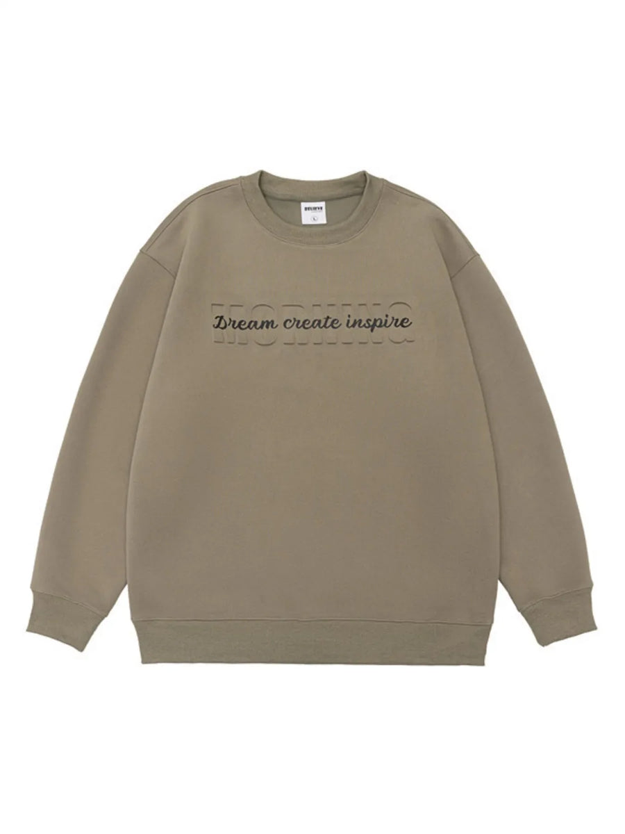 Oversized khaki crew-neck sweatshirt with embossed "MORNING" and "Dream create inspire" text.