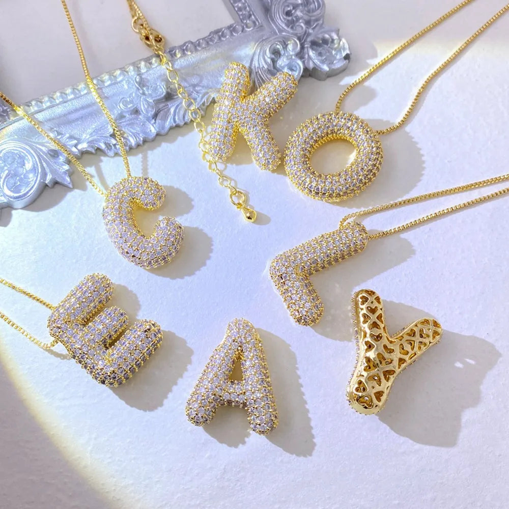 Puffed initial necklaces with zirconia and delicate gold chains, featuring letters C, K, O, L, E, A, Y.