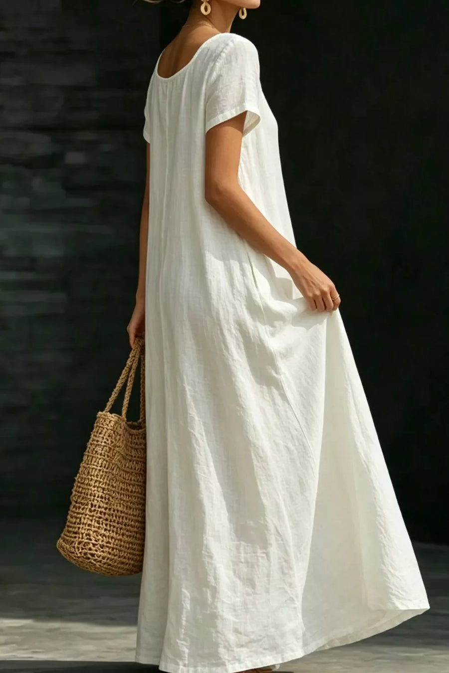 White polyester maxi dress with short sleeves and pockets, styled with a straw bag.