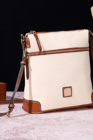 Ivory leather crossbody bag with brown trim and gold hardware, featuring two zip compartments.
