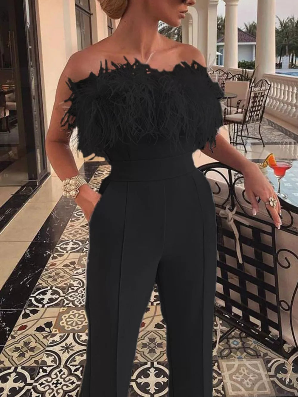 Black strapless feather trim jumpsuit with wide waistband and straight leg pants.