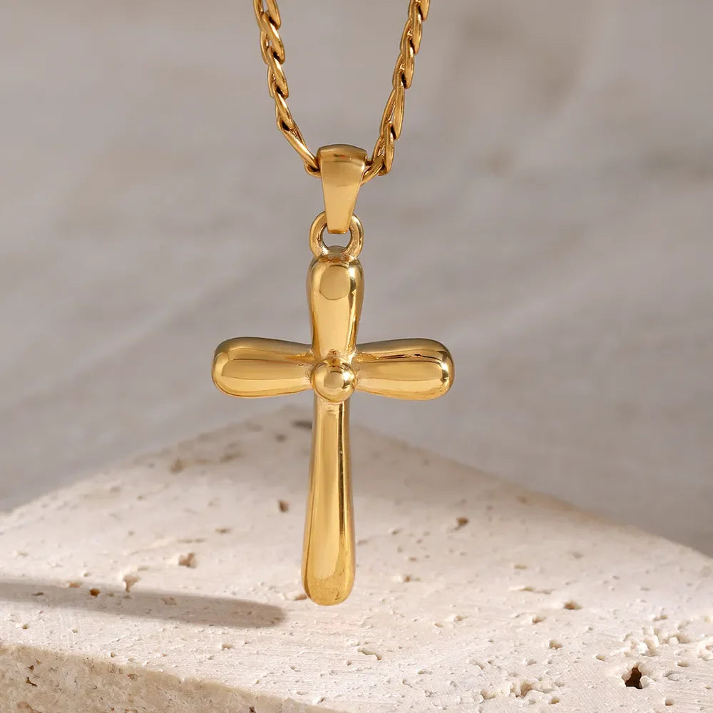 Gold sculpted cross pendant necklace with a curb chain.