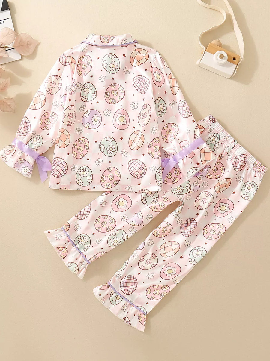 Toddler pajama set with pastel Easter egg print, button-down top, and ruffled cuffs.
