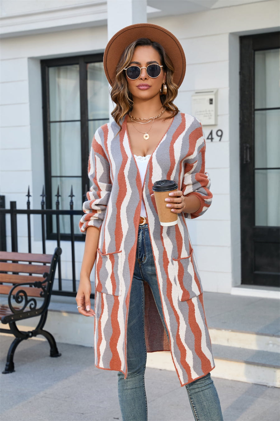 Longline knit cardigan with wave stripe pattern in rust, grey, and white, featuring pockets.