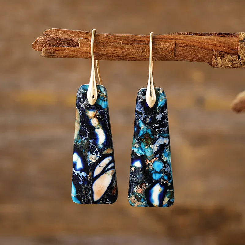 Textured stone drop earrings with gold hooks, featuring blue, black, and white marbled patterns.