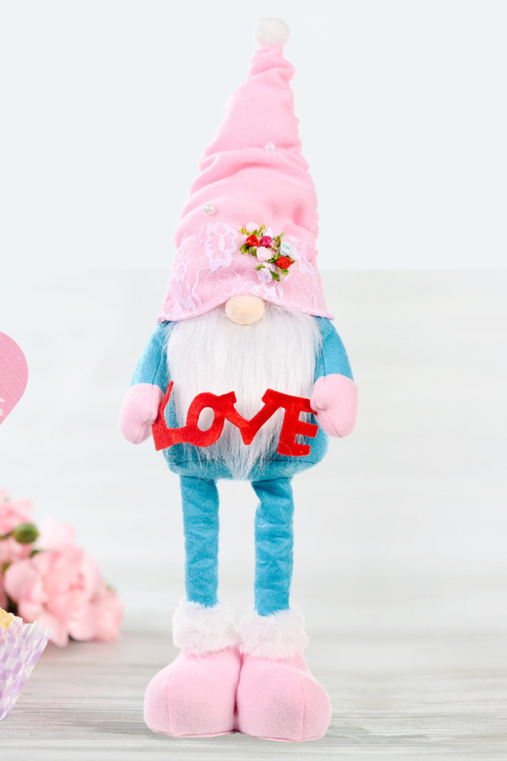 Embroidered gnome with pink hat holding red LOVE sign, blue body, pink boots.