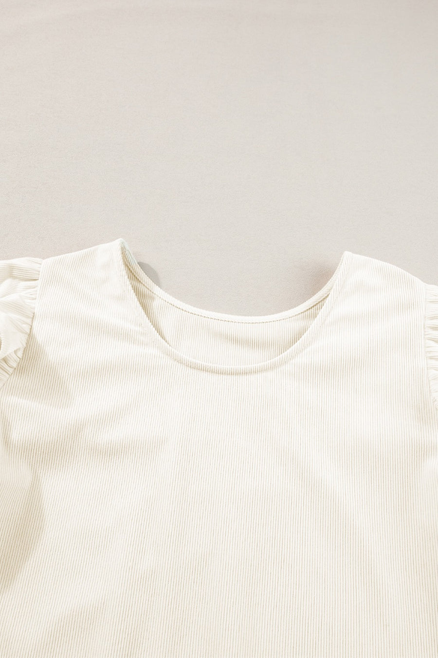 Eggshell textured blouse with ruffle sleeves and a scoop neckline.