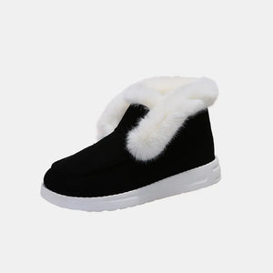 Black suede slip-on booties with white shearling trim and white sole.