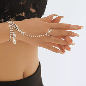 Rhinestone fringe hand chain bracelet in white K with 18K gold plating, connects to a ring.