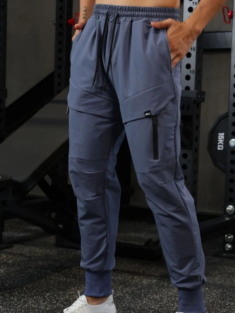 Gray technical joggers with zip detail and cargo pockets.