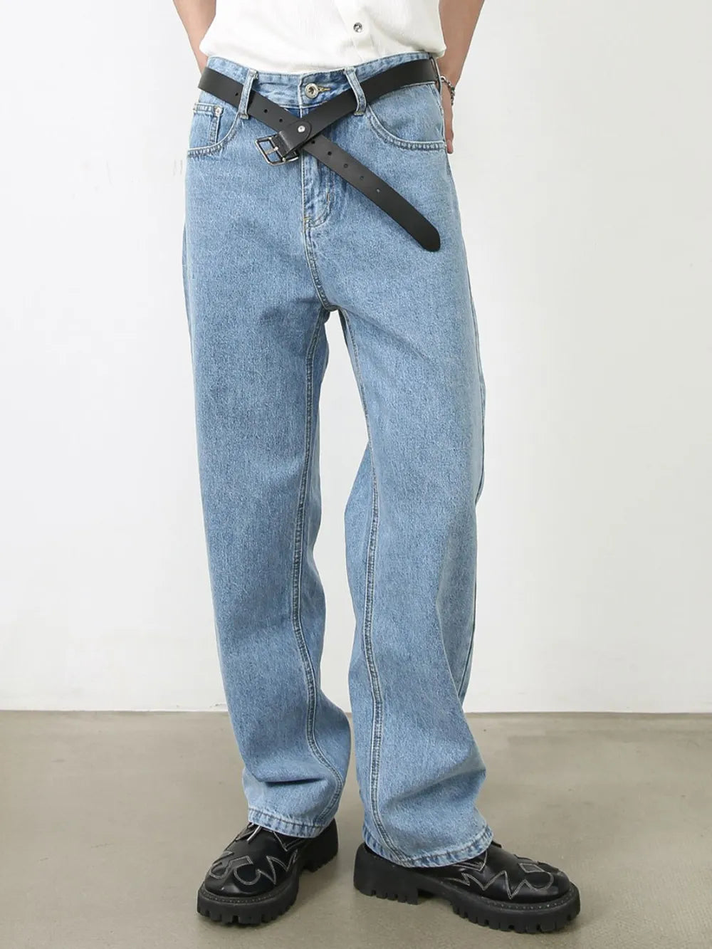 Light blue relaxed-fit denim jeans with subtle seam detail and a black belt.