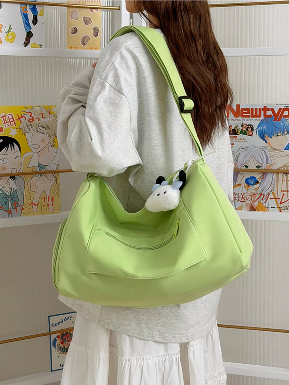 Light green travel bag with adjustable strap and front pockets, worn by a woman.