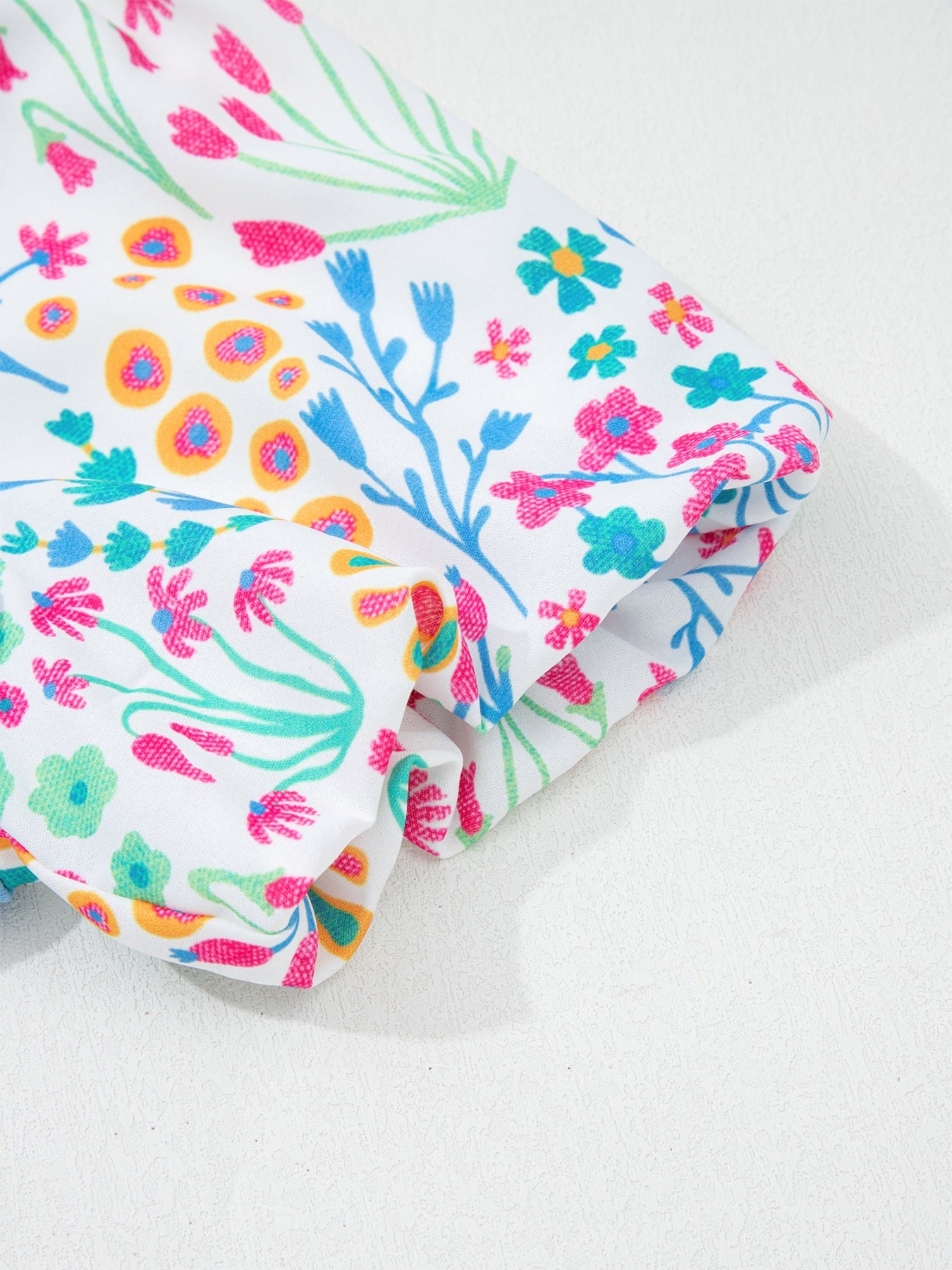 Textured floral bubble sleeve blouse with abstract floral print in pink, blue, and yellow on white.