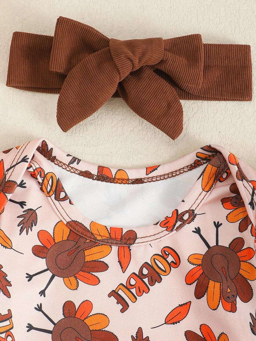 Baby bodysuit with Thanksgiving turkey print and brown corduroy bow headband.