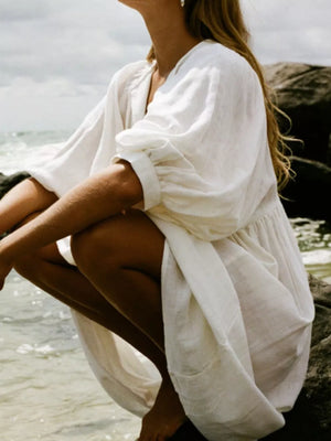 White tie-neck midi dress with puff sleeves and gathered waist detail.