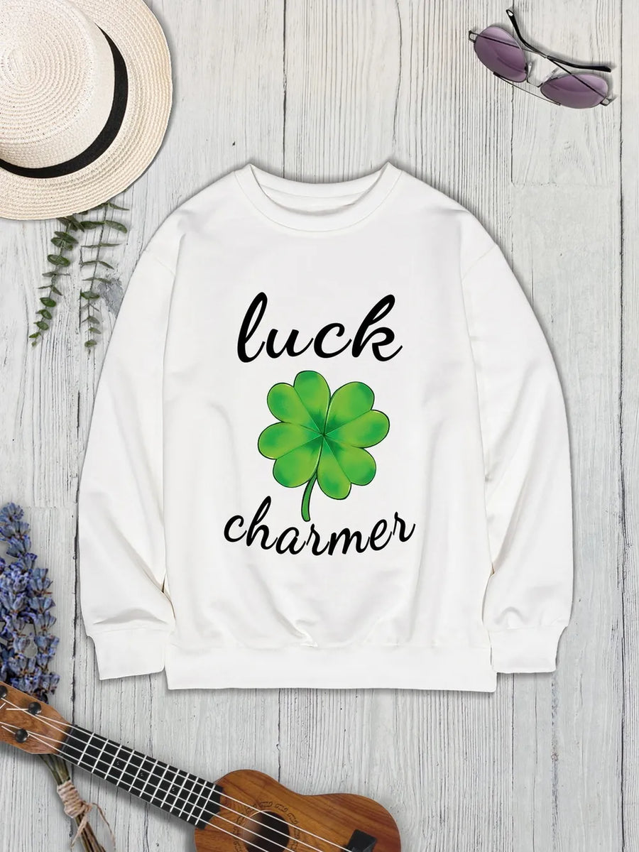 White graphic sweatshirt with a green clover and "luck charmer" text.