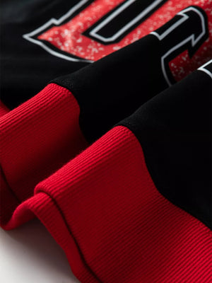 Black sweatshirt with red ribbed cuffs and varsity-style graphic detail.