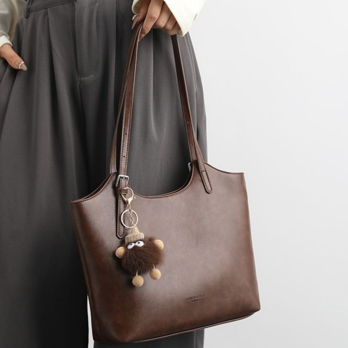 Brown pu leather tote bag with adjustable straps and a cute charm.