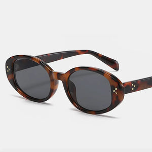 Tortoiseshell oval sunglasses with gold star embellishments and dark lenses.