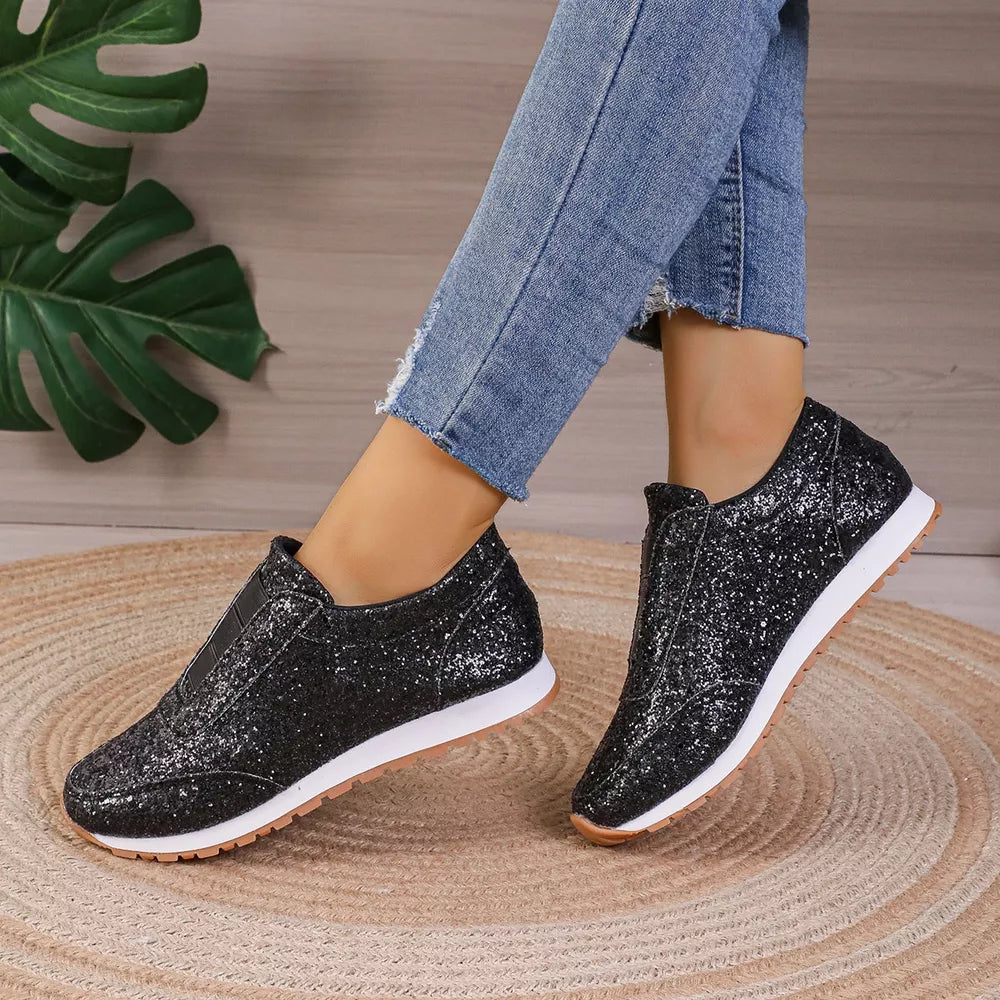 Black glitter slip-on flats with round toe and white soles.