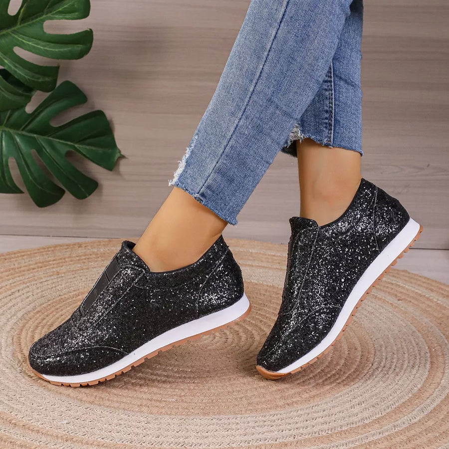 Black glitter slip-on flats with round toe and white soles.