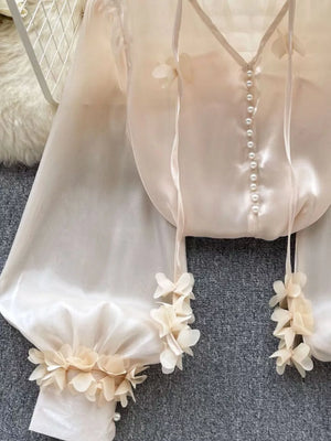 Apricot sheer organza shirt with pearl buttons and delicate floral appliqué on sleeves and hem.