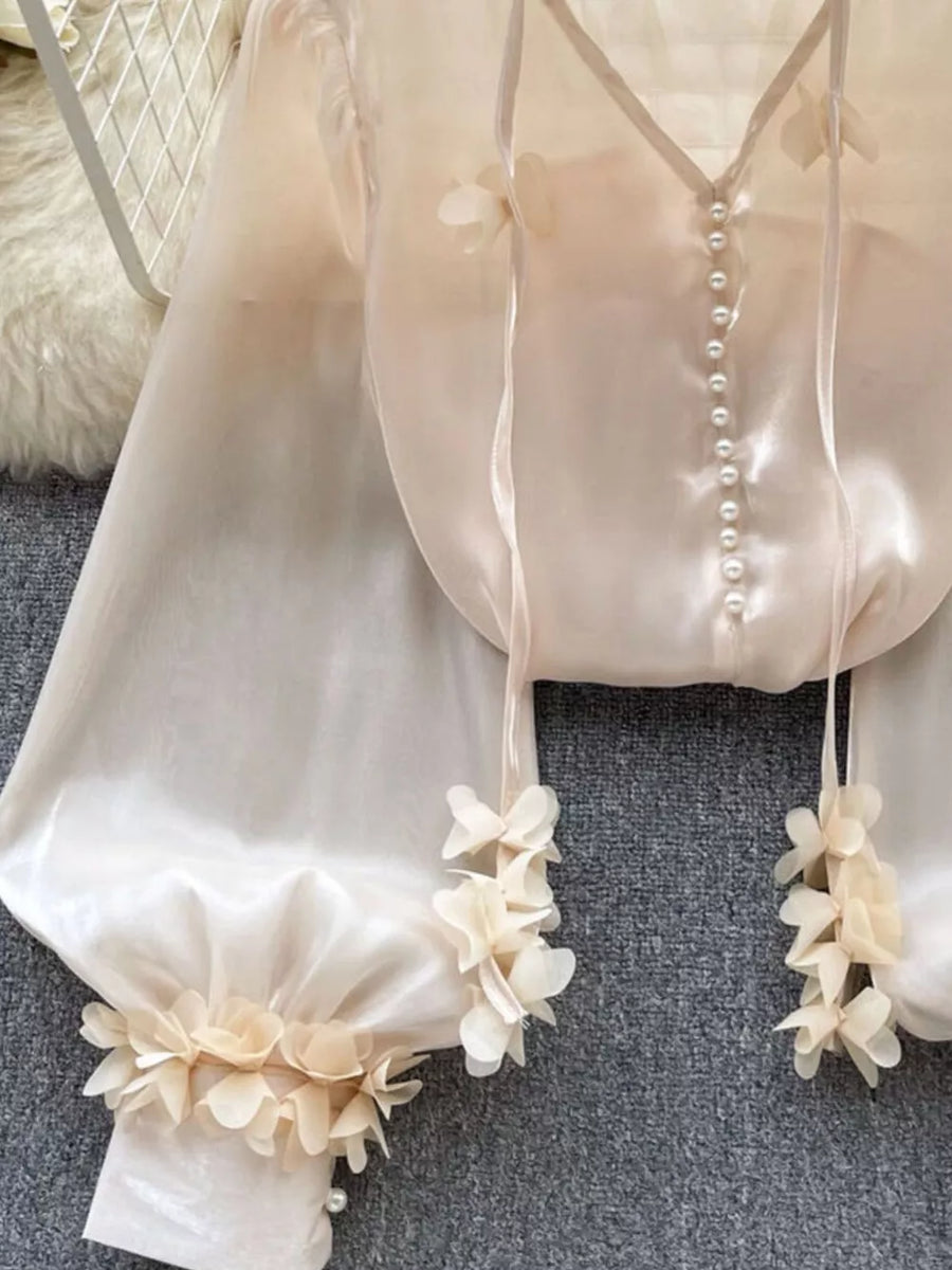 Apricot sheer organza shirt with pearl buttons and delicate floral appliqué on sleeves and hem.