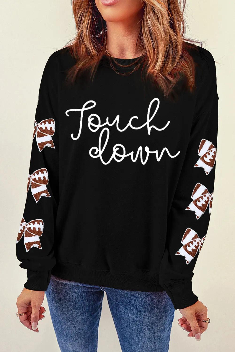 Black sweatshirt with white "Touchdown" script and football bow sleeve embellishments.