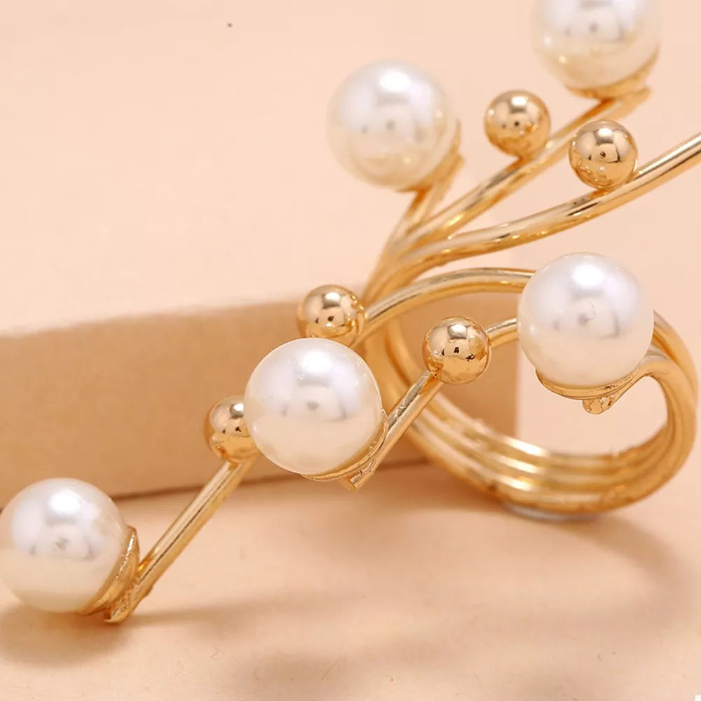 Gold bypass ring with pearls and gold beads on a swirling band.