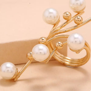 Gold bypass ring with pearls and gold beads on a swirling band.