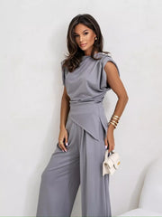 Gray satin cowl neck two-piece set with wide-leg pants and asymmetrical top.